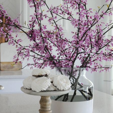 cuttings from a redbug tree are featured in a glass vase and placed outside the bedroom