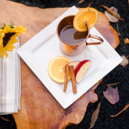 Copper mug of apple cider with orange slice in an outdoor setting