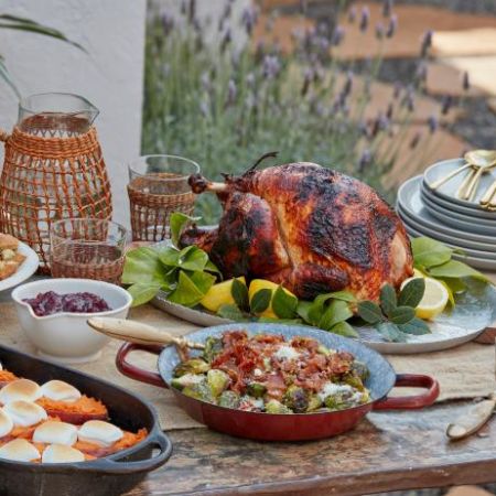 a thanksgiving feast is laid out on a backyard table decorated with a rustic feel