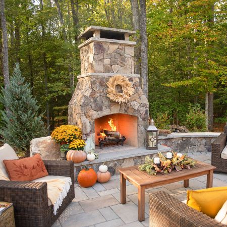 This outdoor large fireplace and lounge seating is decorated with mums and pumpkins for the fall
