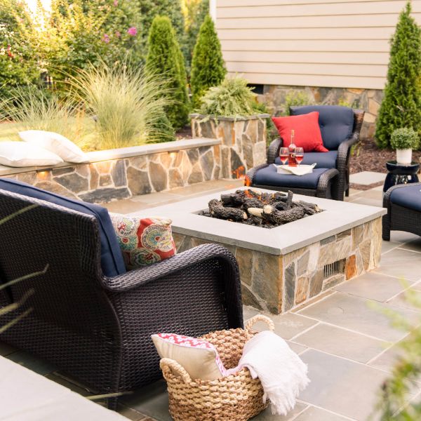 Wicker outdoor chairs and sitting wall surround the gas fire pit