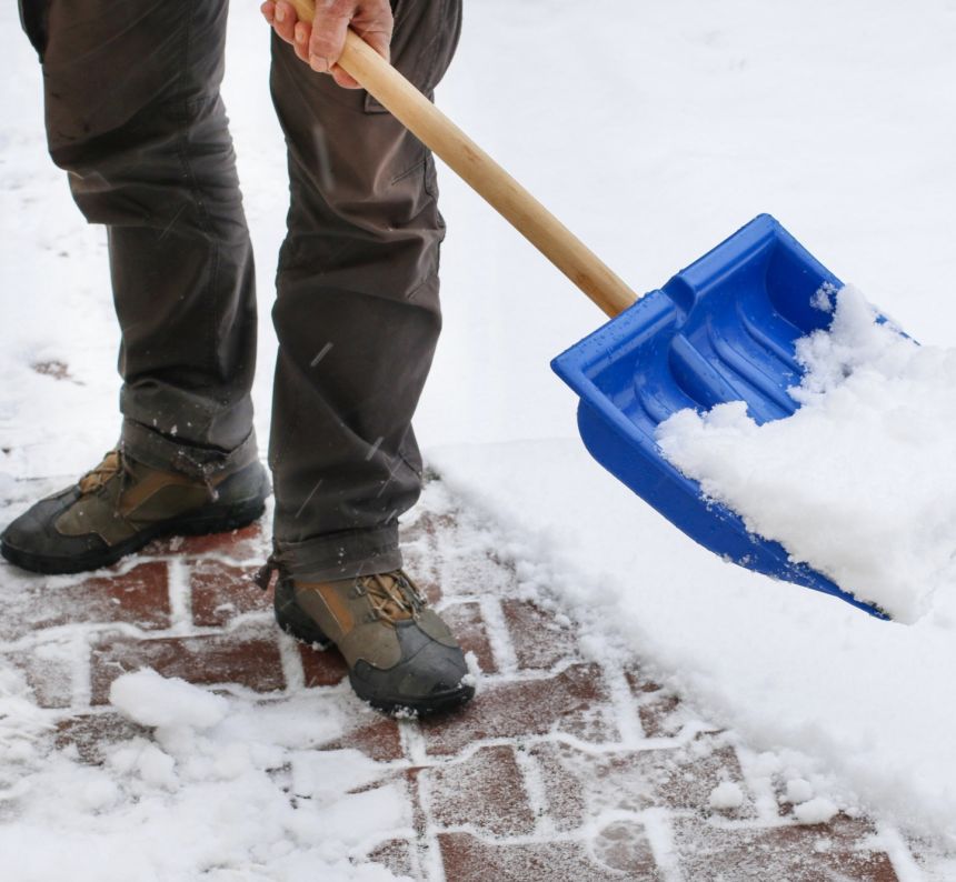 man shoveling snow with blue plastic snow shovel