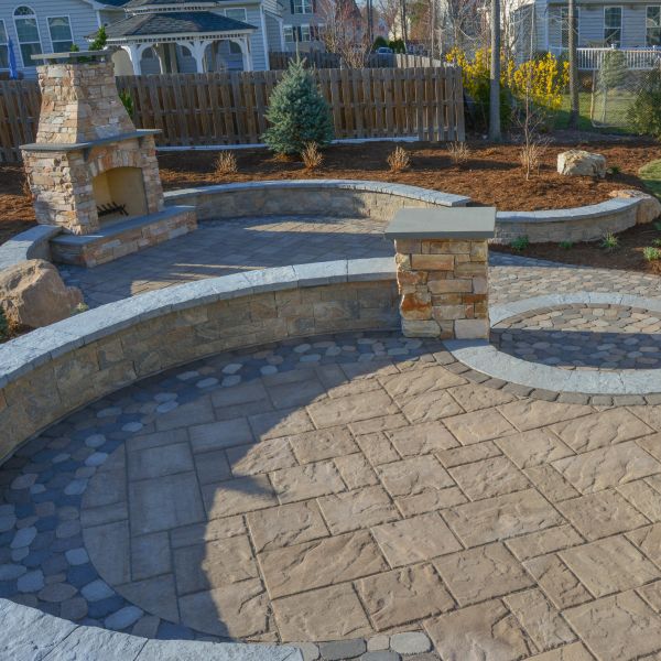 patio with curved sitting wall and stone fireplace feature