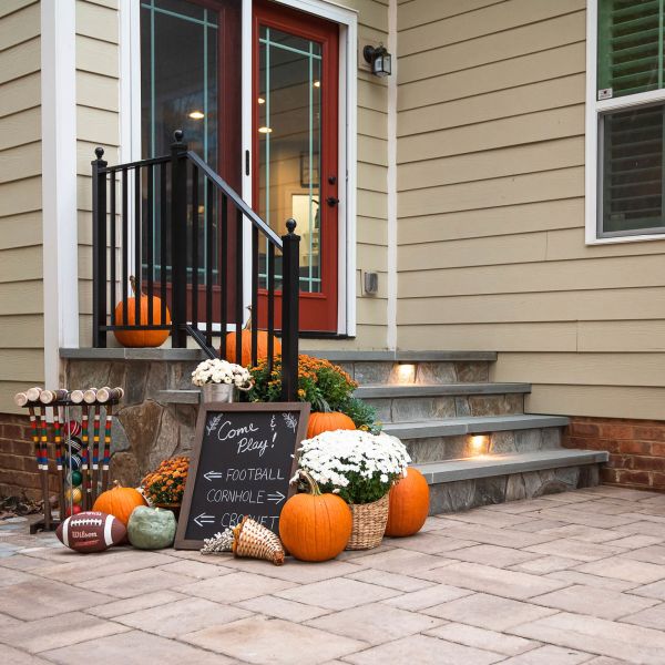 stone steps leading from paver patio to the back door and decorated for fall with pumpkins, football and croquet