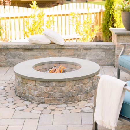 This stone circular fire pit is installed into the patio near the knee wall