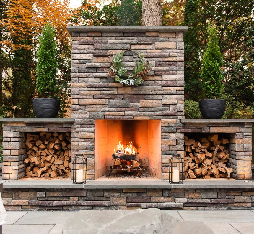 Stone patio with wood burning outdoor fireplace with two wood boxes