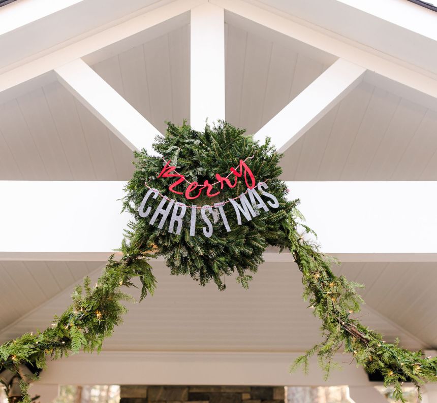 a Christmas wreath is mounted atop the white pavilion and decorated with lit up garland