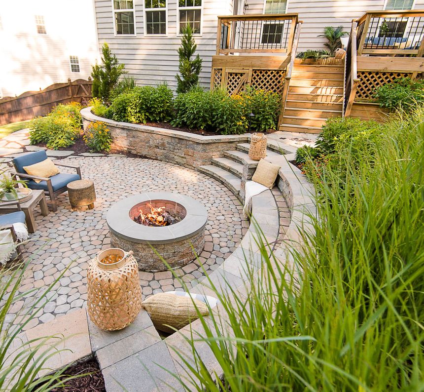 Wood deck and paver patio with fire pit, retaining walls, and landscaping