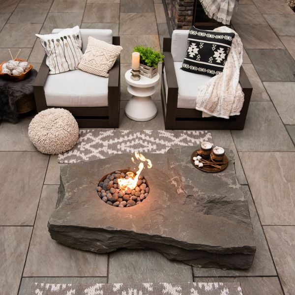 massive grey gas-burning fire pit between beautiful outdoor chairs