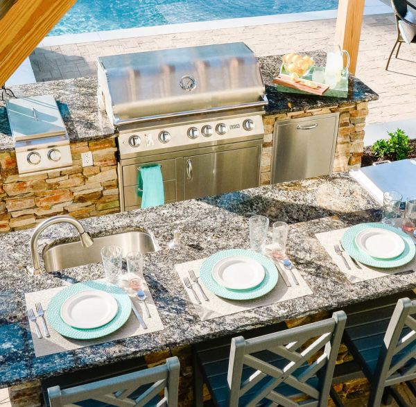 Two island outdoor kitchen with grill, storage, and game day party setup