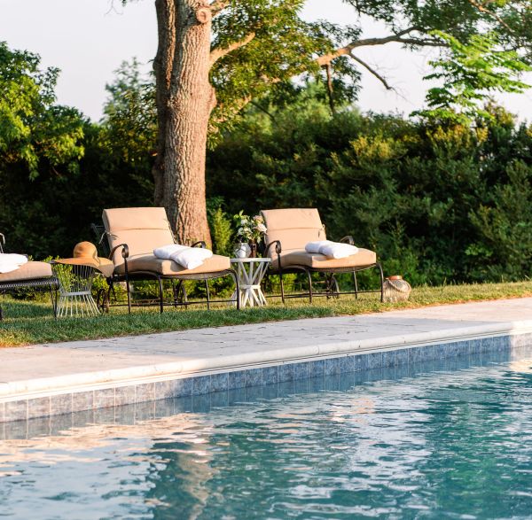 Gunite fiberglass swimming pool with sofa and stone wall