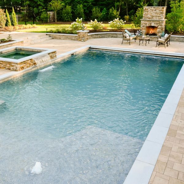 Fiberglass underground pool installed by the hot tub and fire place