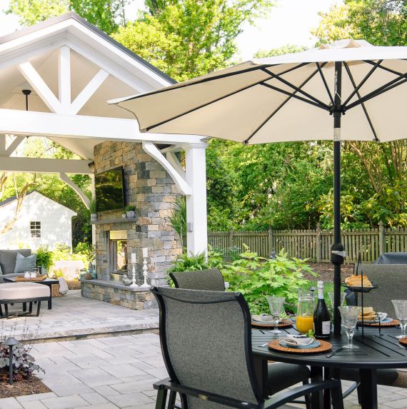 White pavilion stretches over the lounge area of a backyard patio area