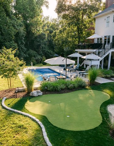 Backyard pool in front of an outdoor fireplace and pergola