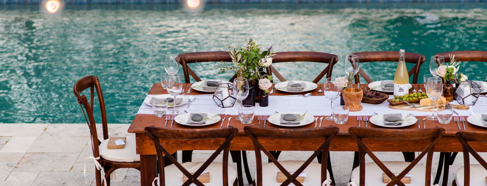 Gunite swimming pool with travertine pool decking and dining table