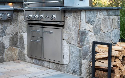 Outdoor kitchen with stone veneer, granite counter, and premium grill