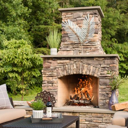 large stone faced fire place is installed into the backyard patio