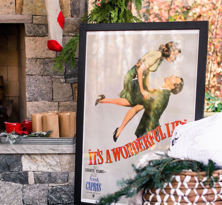 large framed poster from It's a wonderful life sits up next to the outdoor fireplace