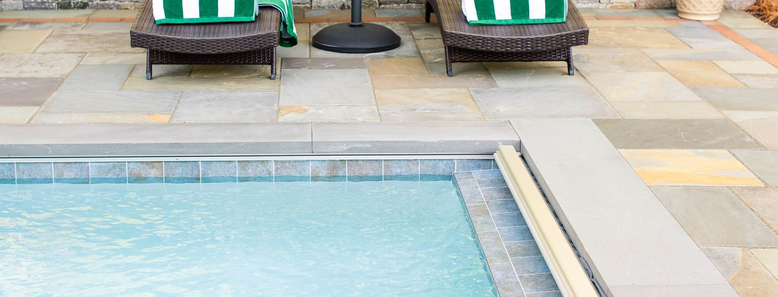 Gunite pool with stone patio and two deck chairs