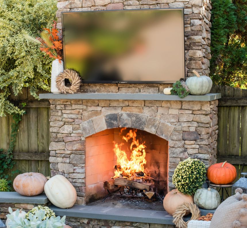 Fall outdoor fireplace with outdoor television and pumpkins