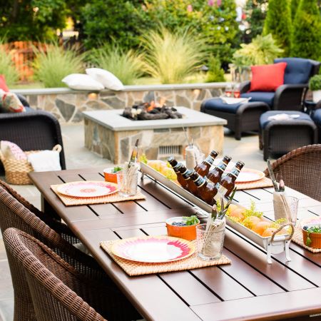 the outdoor table is set for cocktail hour nearby the gas-burning fire pit