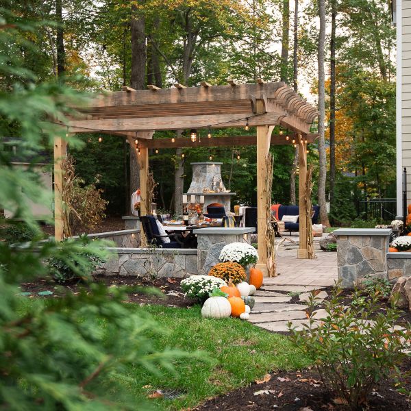 Rustic dark stain pergola on paver patio covering sitting area of large backyard space