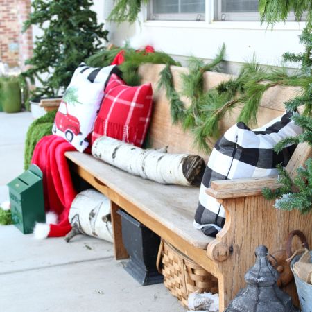 long wooden bench is decorated with pillows and garland for Christmas