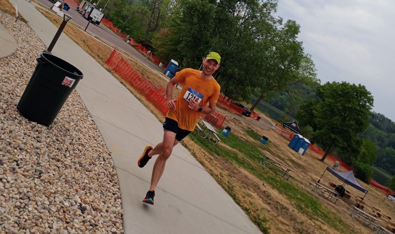 Blog author running in Eagle Chase race on a paved path between picnic tables and trash cans