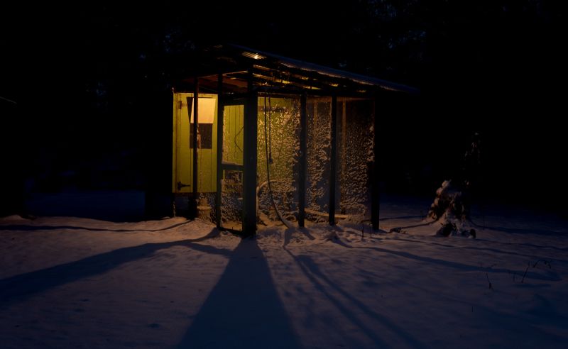 A lighted chicken coop casting shadows in the early morning dark