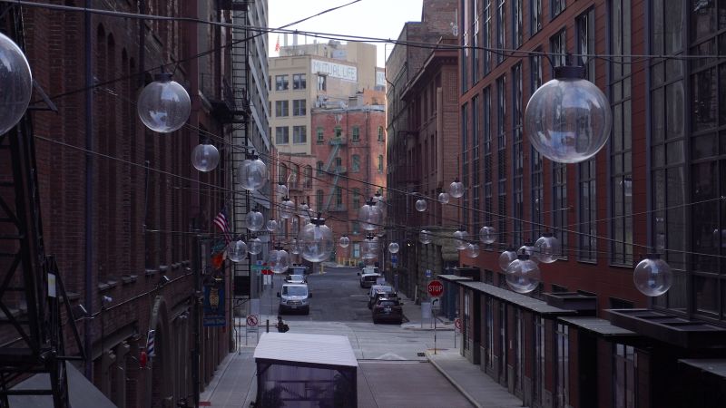 a view down an urban alley with hanging glass orb lights