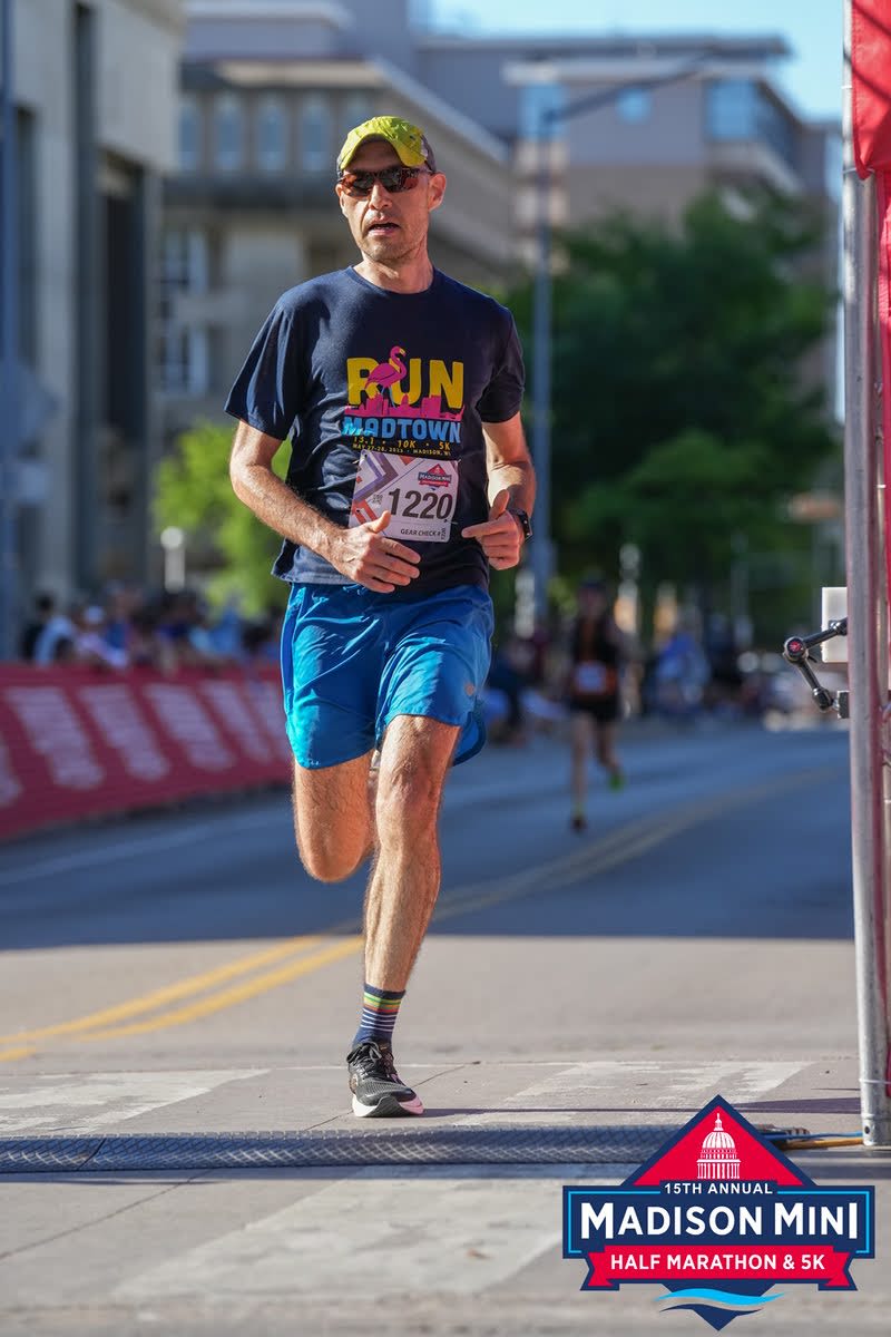 Blog author running in Madison Mini half marathon crossing the finish line