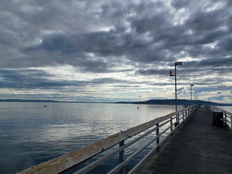 Fishing pier extending out into a bay with over calm water with mountains in the distance