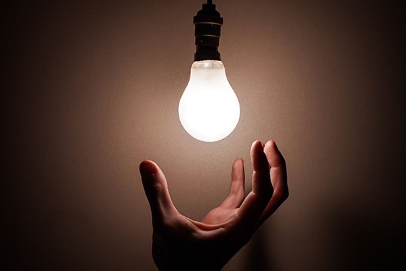 A hand tries to grab a light bulb.