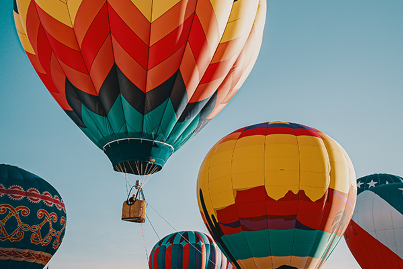 A couple of hot air balloons soar in the sky at sunset. 