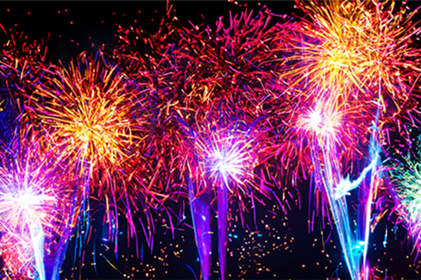 Fireworks of purple, pink, and orange, explode in the sky.