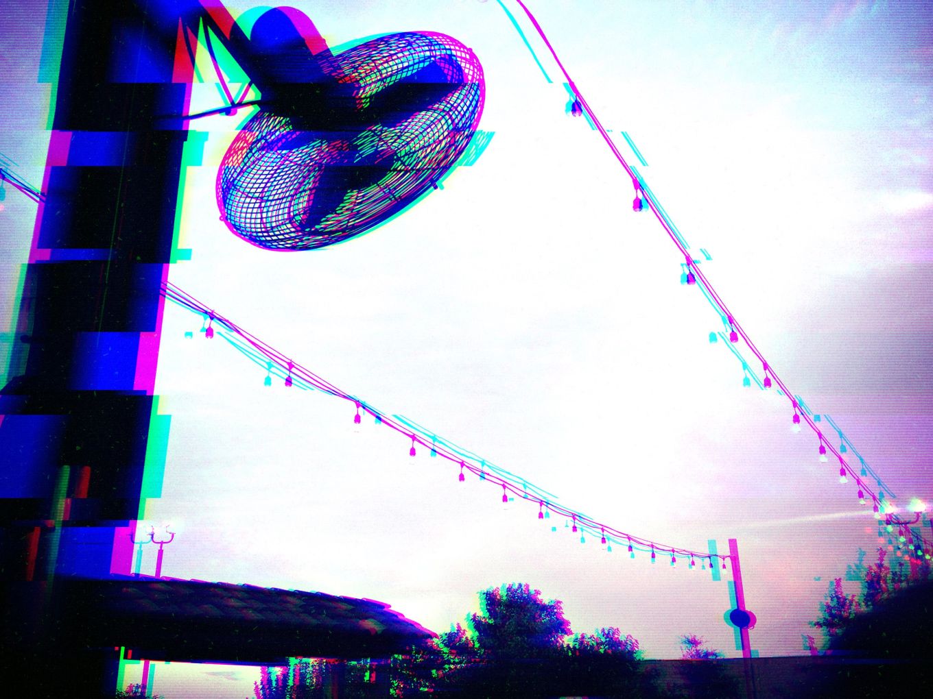 Photo of a fan mounted on a pole. It's outside on a patio with string lights crossing the pavilion.