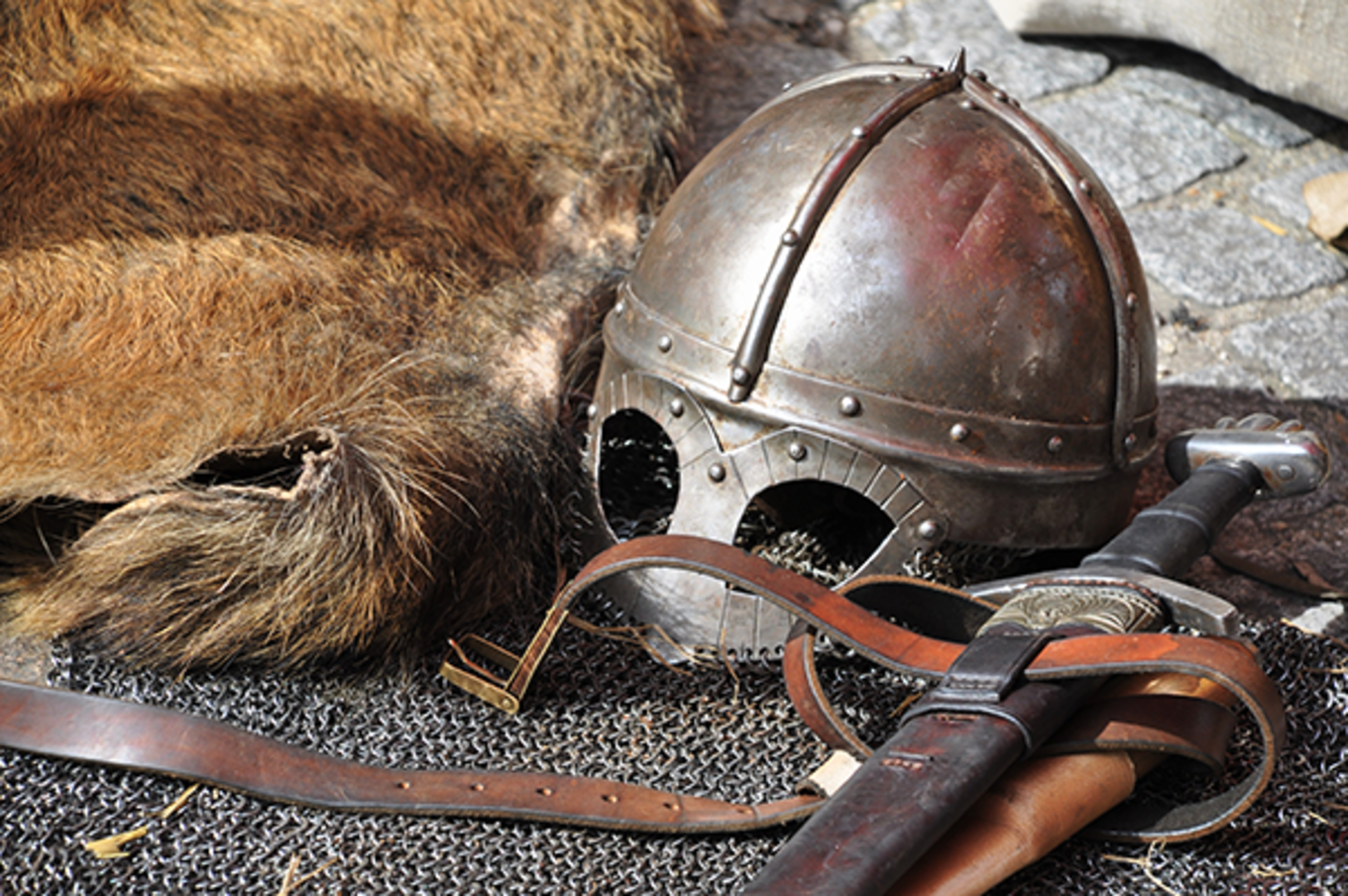 Medieval armor and helmet over a chainmail floor.