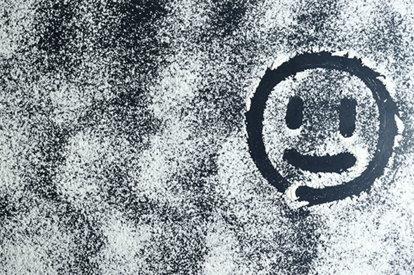 A spray-painted, kind-of-smiling emoji, on a concrete-like, textured background.