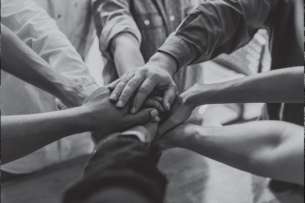 several people putting hands together at center of a circle