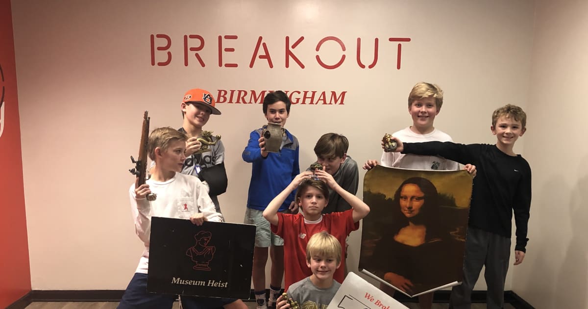 Group of kids posing with their escape time written on a board at an escape room