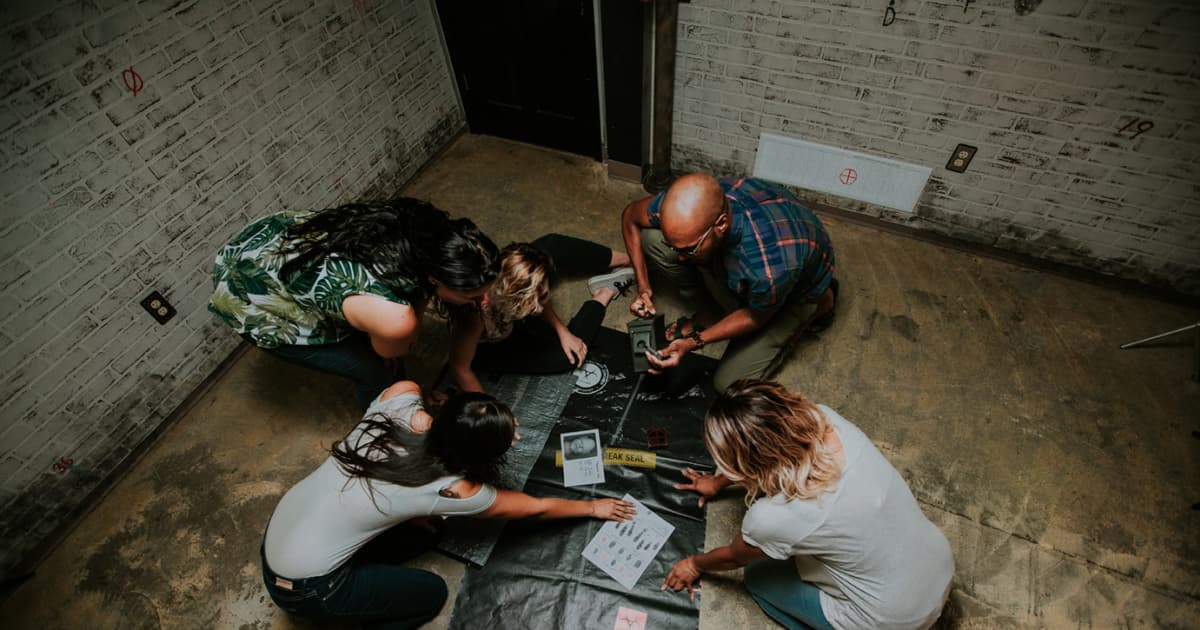 four people on the ground looking at a map and searching for clues