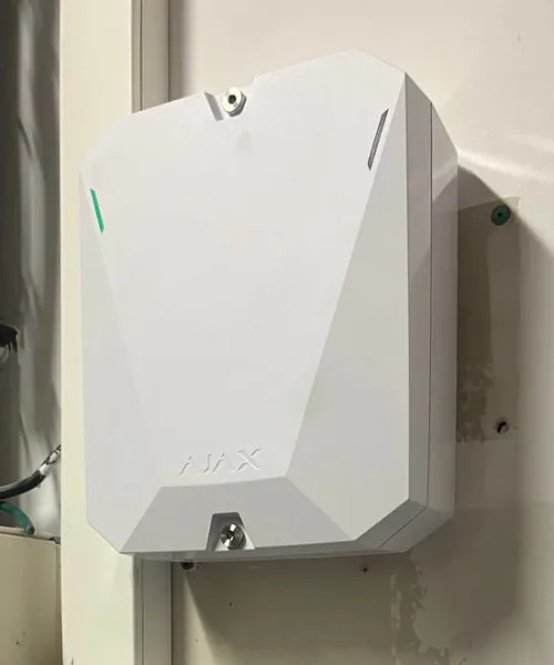 Centrale d'alarme Ajax Hub Hybrid fixée au mur, capot fermé, voyant vert allumé