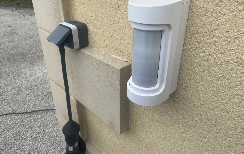 Détecteur extérieur fixé en angle de façade, près d'une descente de gouttière