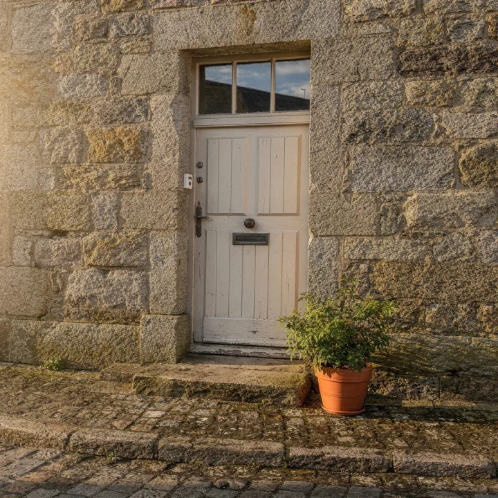 Porte d'entrée en bois dans une façade de granit, rue pavée