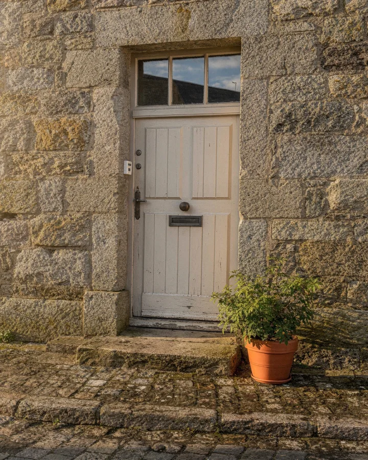 Porte d'entrée en bois dans une façade de granit, rue pavée