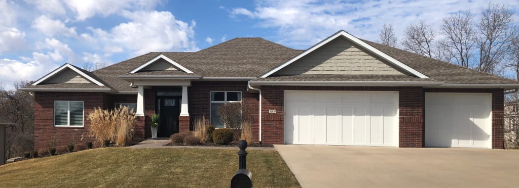 An exterior photo of a brick home with white front porch columns