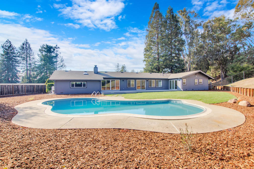 An actual after photo of the backside of a home with a pool in the yard