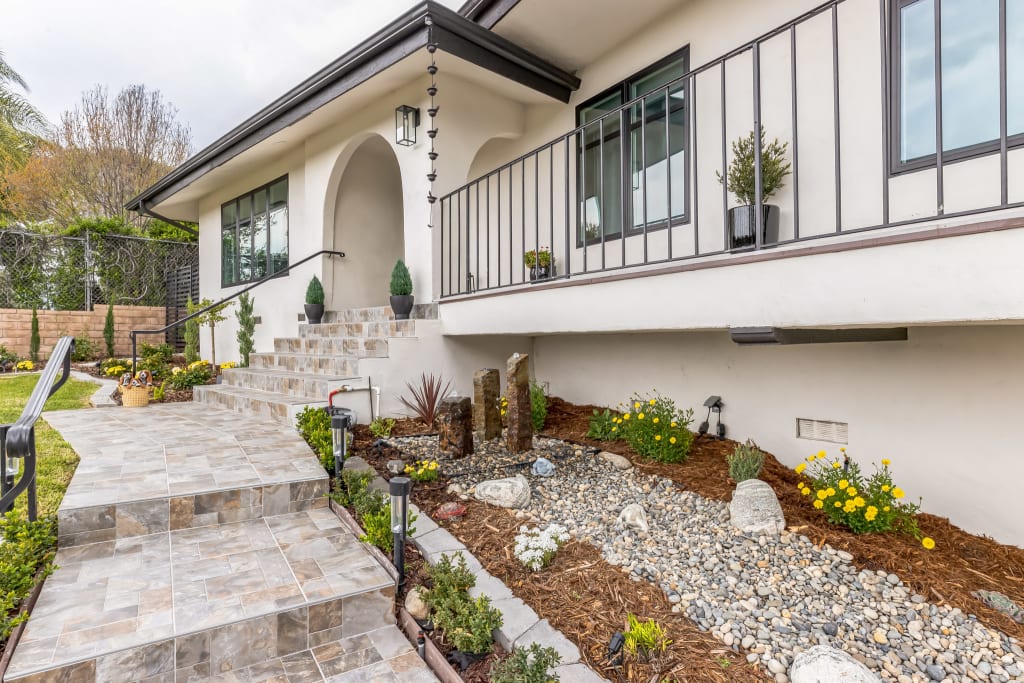 A close up of a white stucco home with black windows