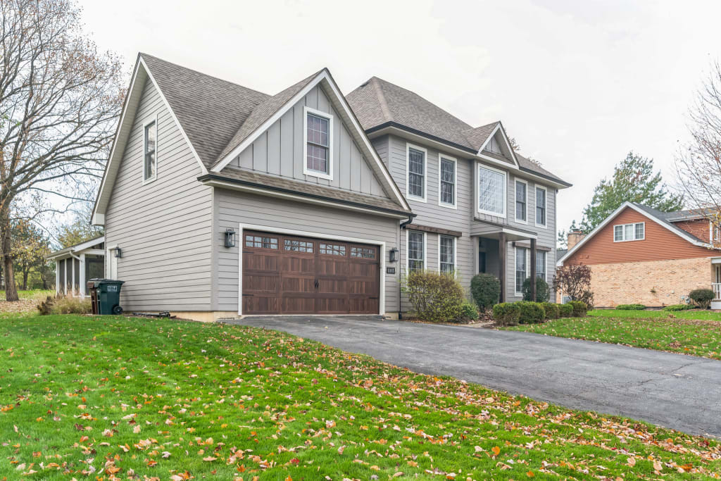 Angled shot of a two-story home exterior showcasing gray siding and wooden garage door.