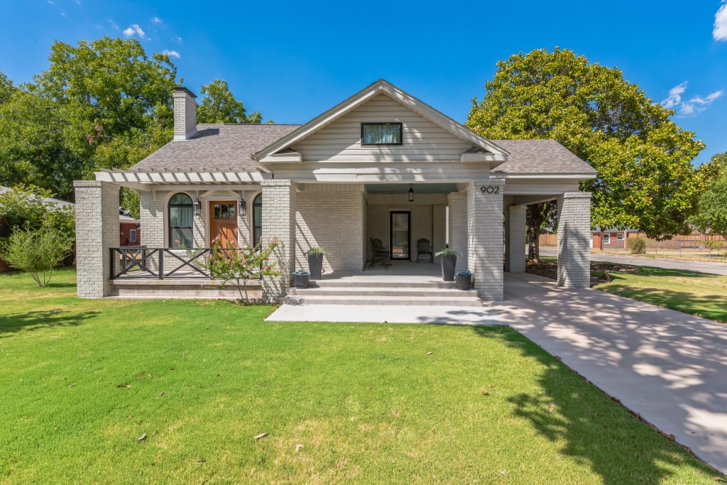 Home exterior with greige painted brick, a covered porch, and black trim.